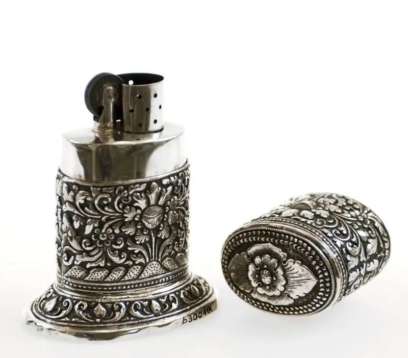 Floral silver table lighter with its matching removable lid beside it